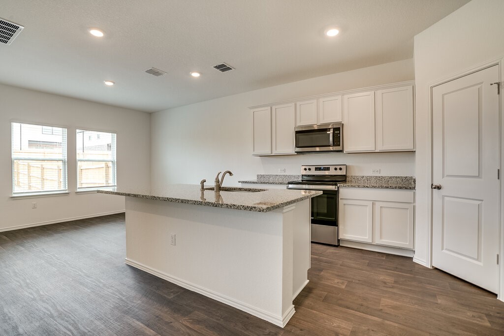 14824 Grey Ghost Way, Unit A Manor, TX 78653 - Photo 7 of 20 a kitchen with granite countertop a sink and steel appliances