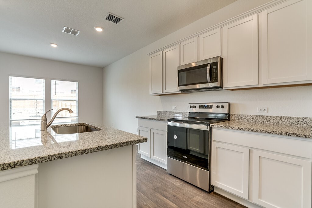 14824 Grey Ghost Way, Unit A Manor, TX 78653 - Photo 8 of 20 a kitchen with granite countertop a sink stainless steel appliances and white cabinets