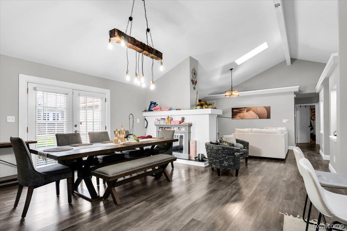 3260 Isabelle Street Inkster, MI 48141 - Photo 16 of 35 Open-concept living area featuring a vaulted ceiling with exposed beams and a skylight, wood-finish flooring, and a fireplace with a mantel