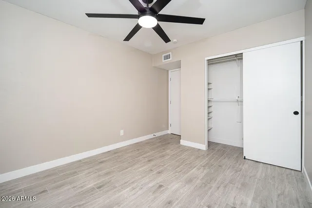 an empty room with wooden floor ceiling fan and window