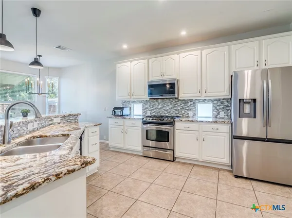 a kitchen with kitchen island granite countertop a sink appliances and cabinets