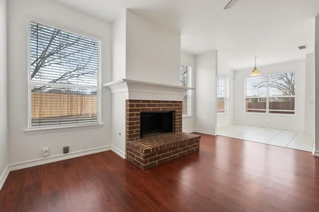 an empty room with wooden floor and a fireplace