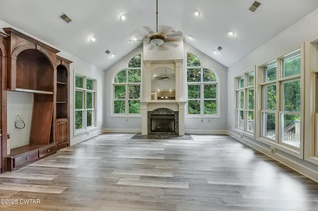 a view of an empty room with wooden floor fireplace and a window