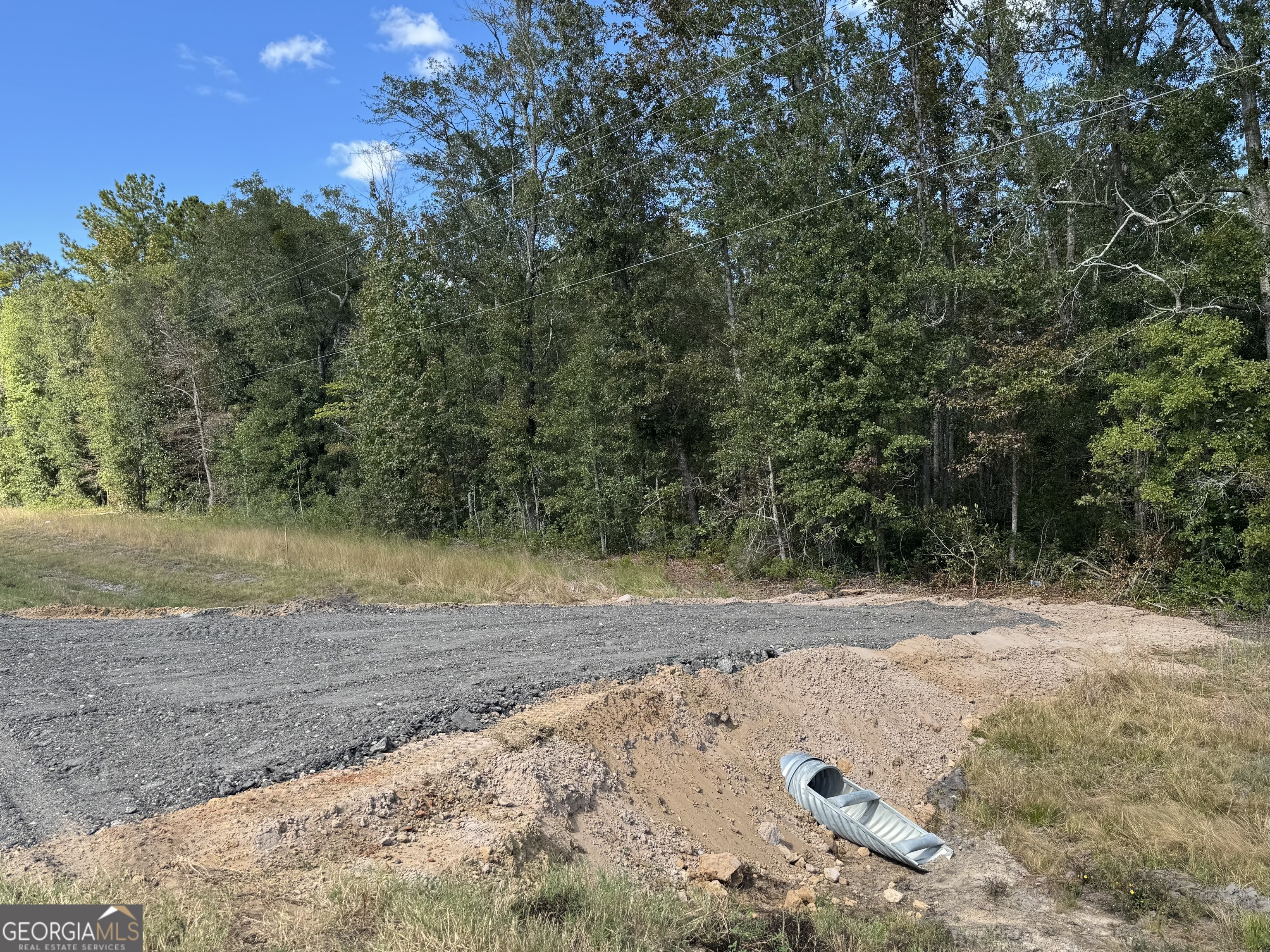 a view of a dirt road with trees in the background