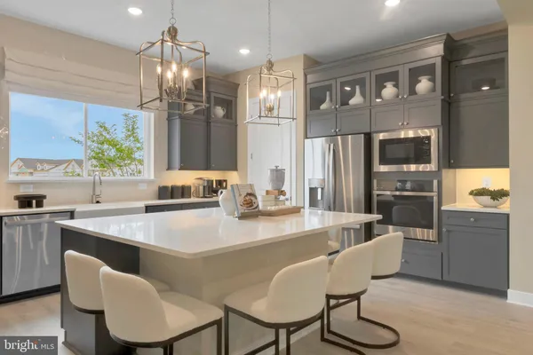 a kitchen with granite countertop a refrigerator a sink a stove a dining table and chairs