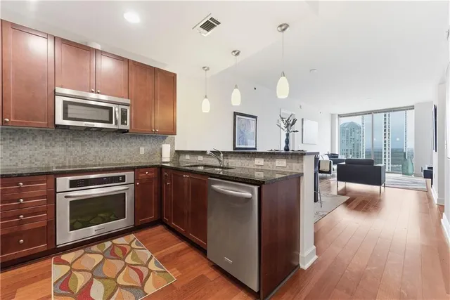 a kitchen with stainless steel appliances granite countertop a stove a sink and a microwave