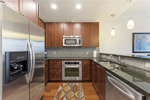 a kitchen with stainless steel appliances granite countertop a stove a sink and a microwave