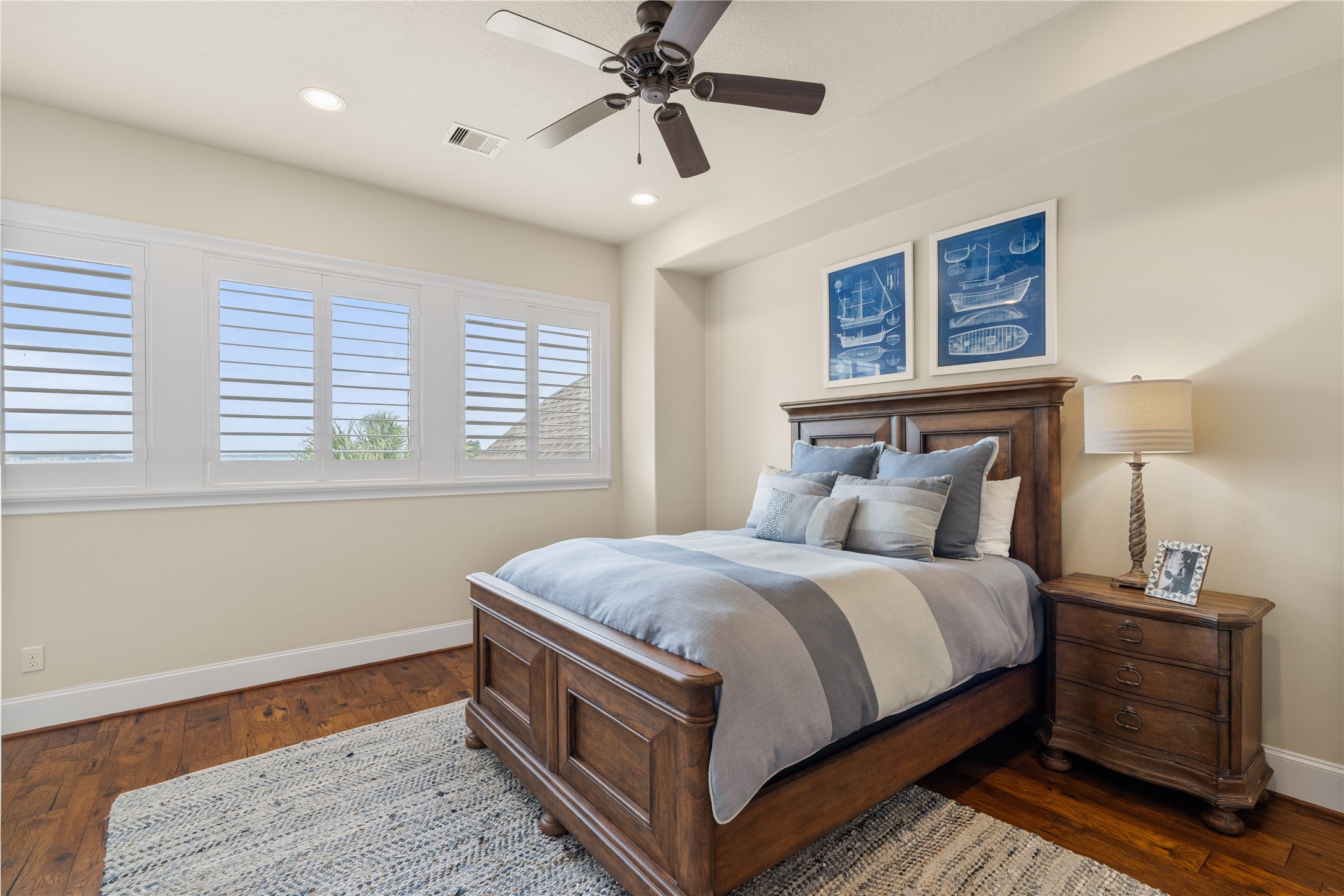 12349 Longmire Trace Conroe, TX 77304 - Photo 25 of 48 Serene bedroom with hardwood floors, ceiling fan, and plantation shutters framing peaceful lake views.