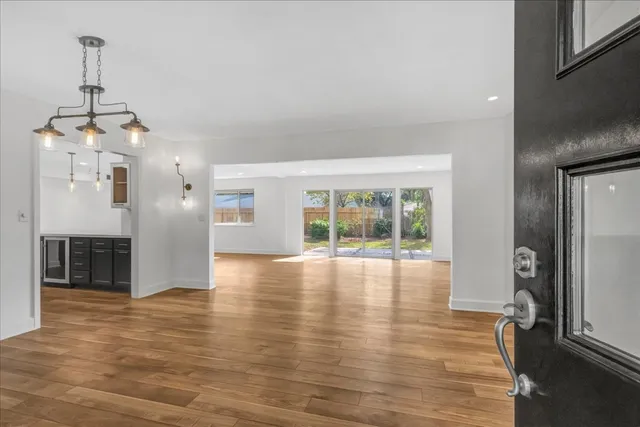 a view of an empty room with window and wooden floor