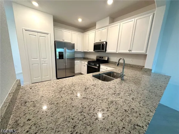 a kitchen with stainless steel appliances granite countertop a sink a stove a refrigerator a microwave and cabinets