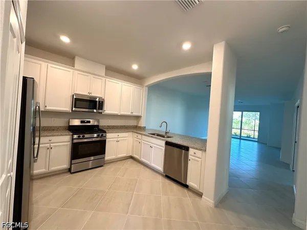a large kitchen with stainless steel appliances granite countertop a stove a sink and a refrigerator