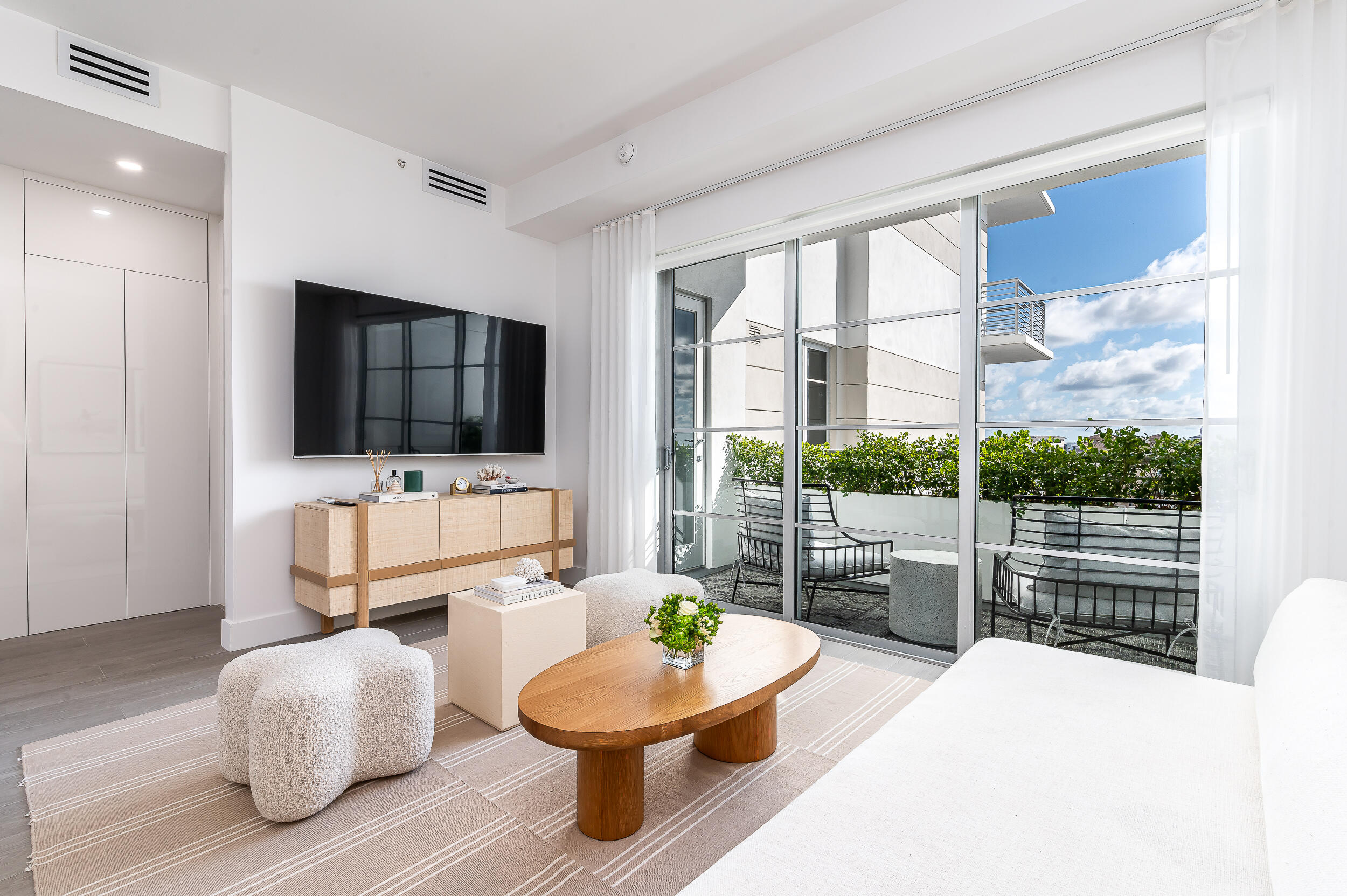 155 East Boca Raton Road, Unit 1008 Boca Raton, FL 33432 - Photo 3 of 42 a living room with furniture a flat screen tv and a floor to ceiling window