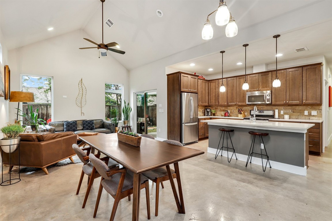 a kitchen with a dining table chairs stainless steel appliances and cabinets