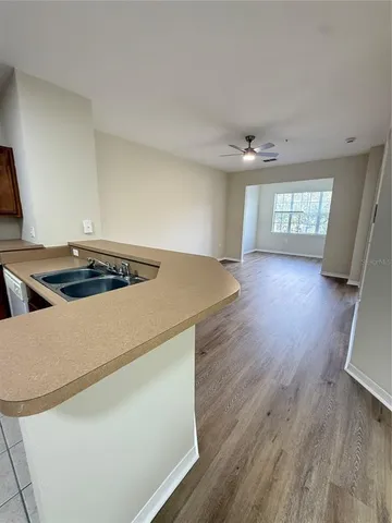 a kitchen that has a lot of cabinets a sink and wooden floor