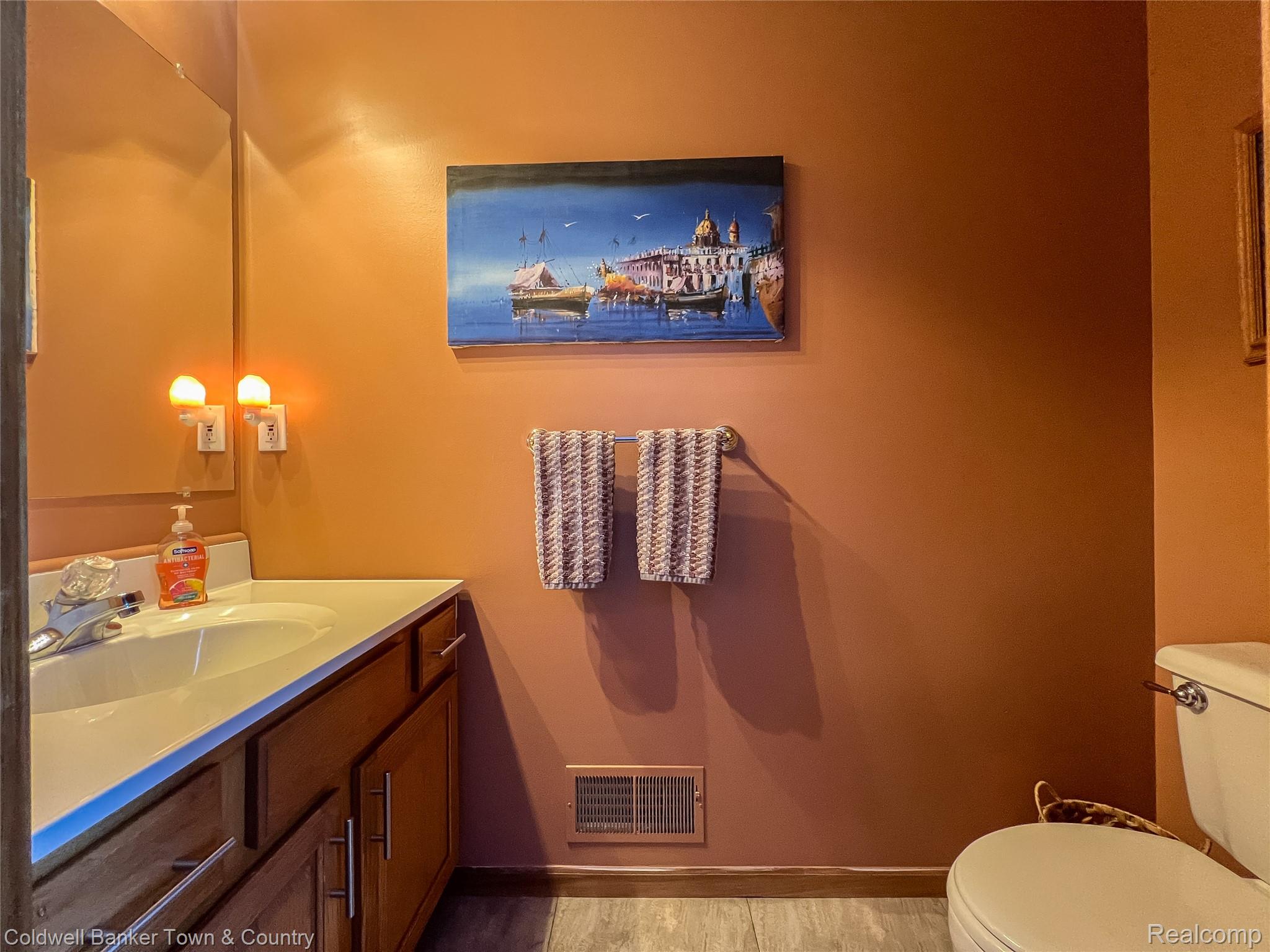717 North Youngs Road Attica, MI 48412 - Photo 28 of 87 Wood-finish flooring complements the vanity with a built-in sink and a wall-mounted mirror