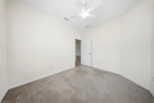 an empty room with a ceiling fan and a window