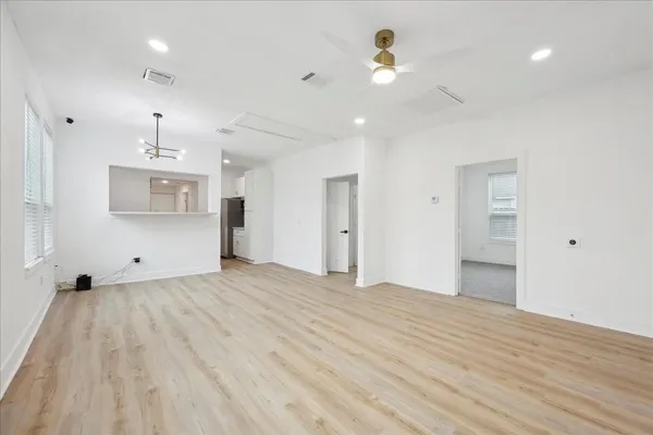 a view of empty room with wooden floor and ceiling fan