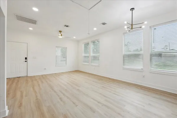 an empty room with wooden floor and windows