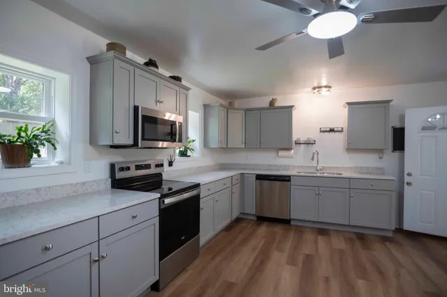 a kitchen with kitchen island granite countertop stainless steel appliances a sink cabinets and wooden floor