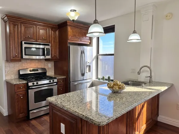 a kitchen with kitchen island granite countertop a stove a sink a refrigerator wooden floor cabinets and dining table
