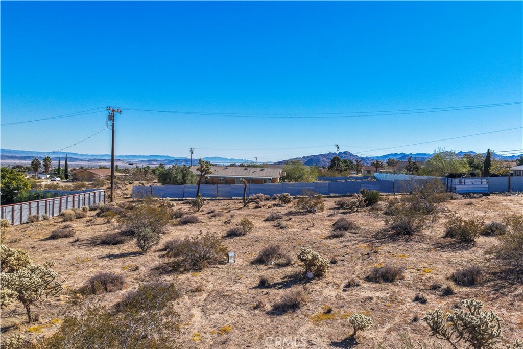 7199 Olympic Road Joshua Tree, CA 92252 - Photo 9 of 12 a view of a dry yard with wooden fence