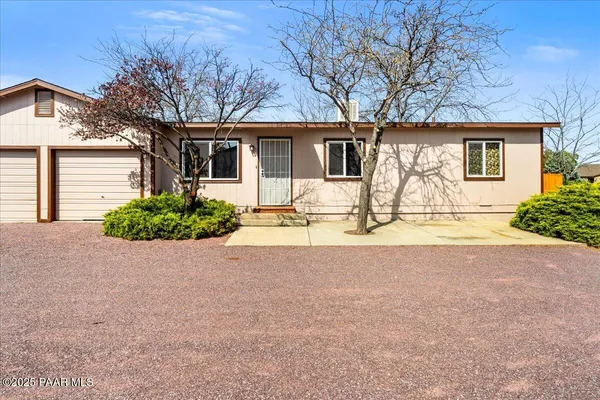 front view of a house with a bench and trees around