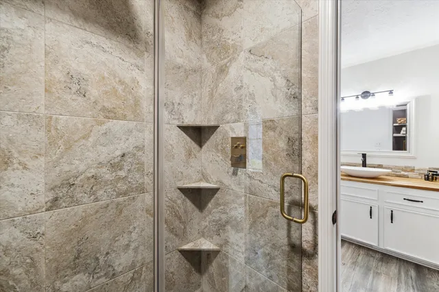 a bathroom with a granite countertop shower a mirror and a sink