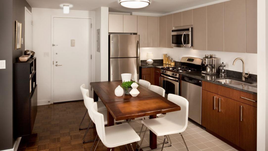 a kitchen with stainless steel appliances a refrigerator a stove a sink a dining table and chairs