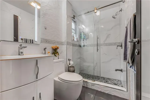 a bathroom with a shower sink vanity and toilet