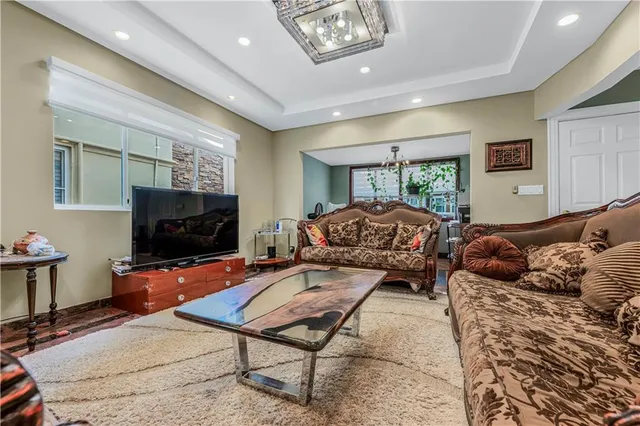 a living room with furniture a flat screen tv and a refrigerator