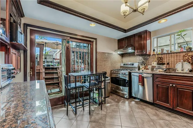 a kitchen with stainless steel appliances granite countertop a stove top oven a sink a dining table and chairs with wooden floor