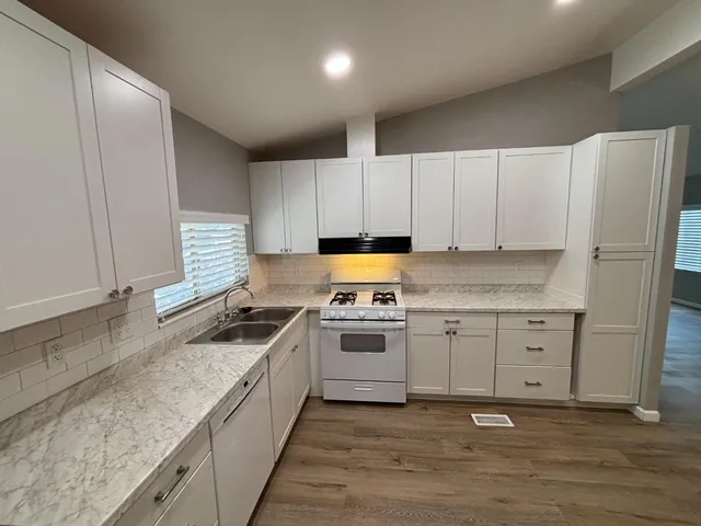 a kitchen with granite countertop a sink stainless steel appliances and cabinets