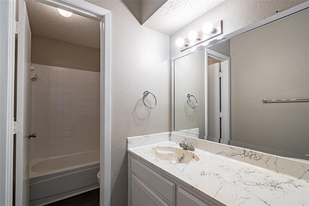 806 Treadwell Court, Unit B Hurst, TX 76053 - Photo 25 of 27 a bathroom with a granite countertop sink mirror and a shower