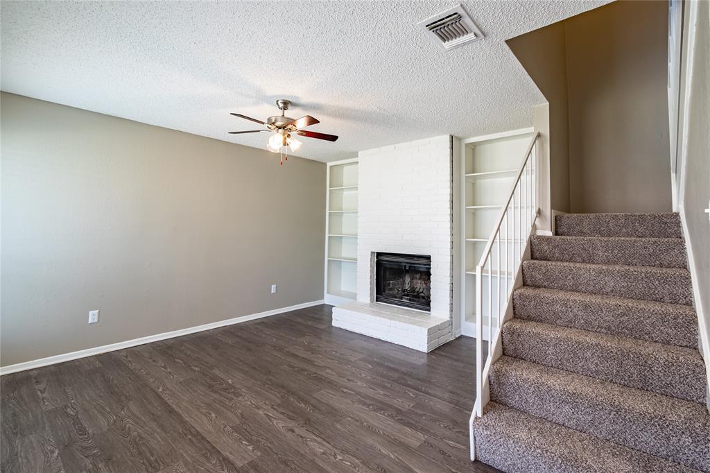 806 Treadwell Court, Unit B Hurst, TX 76053 - Photo 4 of 27 a view of an empty room with wooden floor and a fireplace