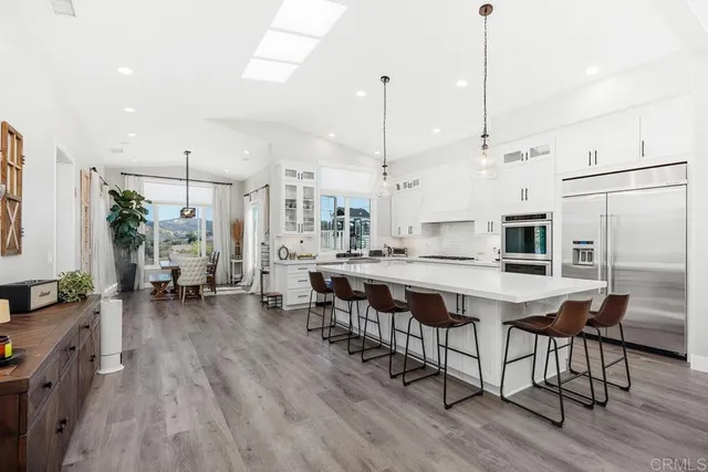 a kitchen island with stainless steel appliances a table chairs refrigerator and sink