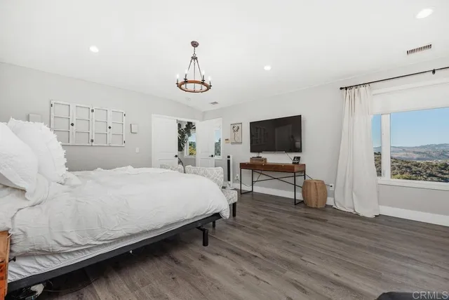 a spacious bedroom with a bed and a flat screen tv