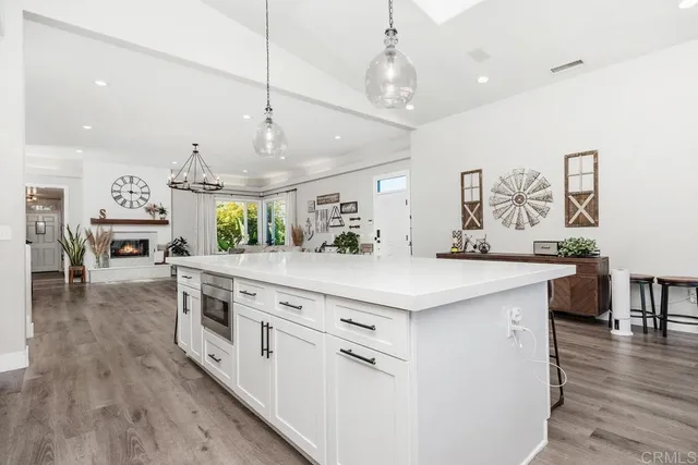 a kitchen with stainless steel appliances granite countertop a white stove top oven a dining table and chairs with wooden floor