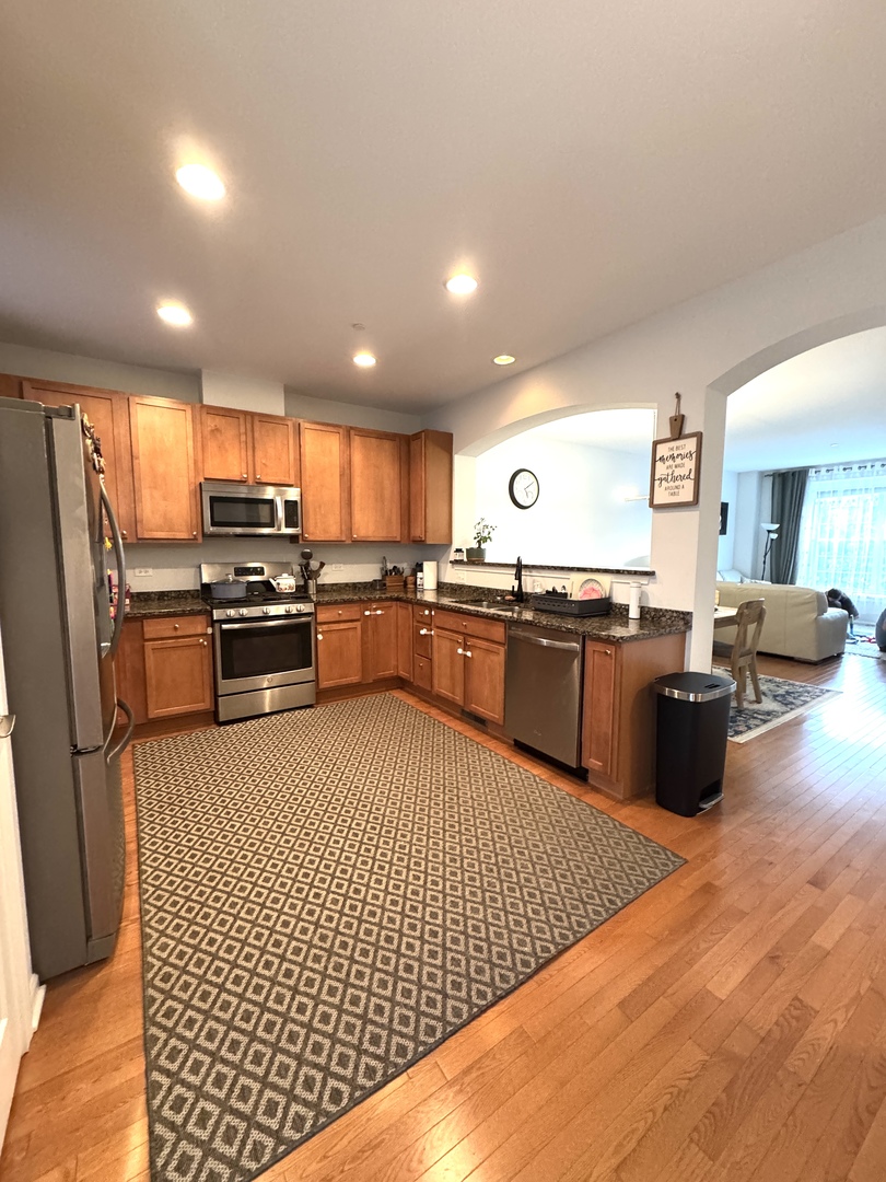 17 East Willow Road, Unit 17 Wheeling, IL 60090 - Photo 4 of 22 a kitchen with stainless steel appliances granite countertop a stove top oven a sink dishwasher a refrigerator and cabinets with wooden floor
