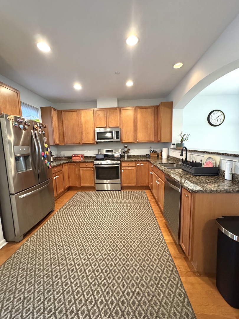 17 East Willow Road, Unit 17 Wheeling, IL 60090 - Photo 5 of 22 a large kitchen with stainless steel appliances granite countertop a stove top oven a sink dishwasher and cabinets with wooden floor