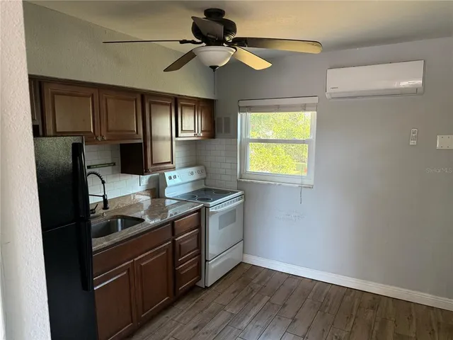 a kitchen with stainless steel appliances granite countertop a refrigerator a sink dishwasher a stove and white countertops with wooden floor