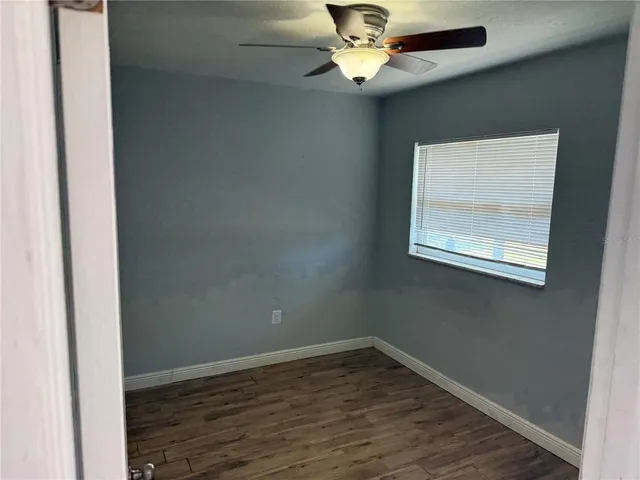 an empty room with wooden floor chandelier fan and window