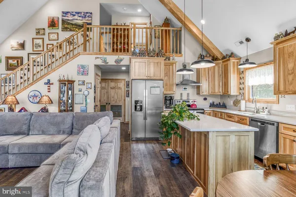 a kitchen with stainless steel appliances kitchen island granite countertop a stove refrigerator and a dining table with wooden floor