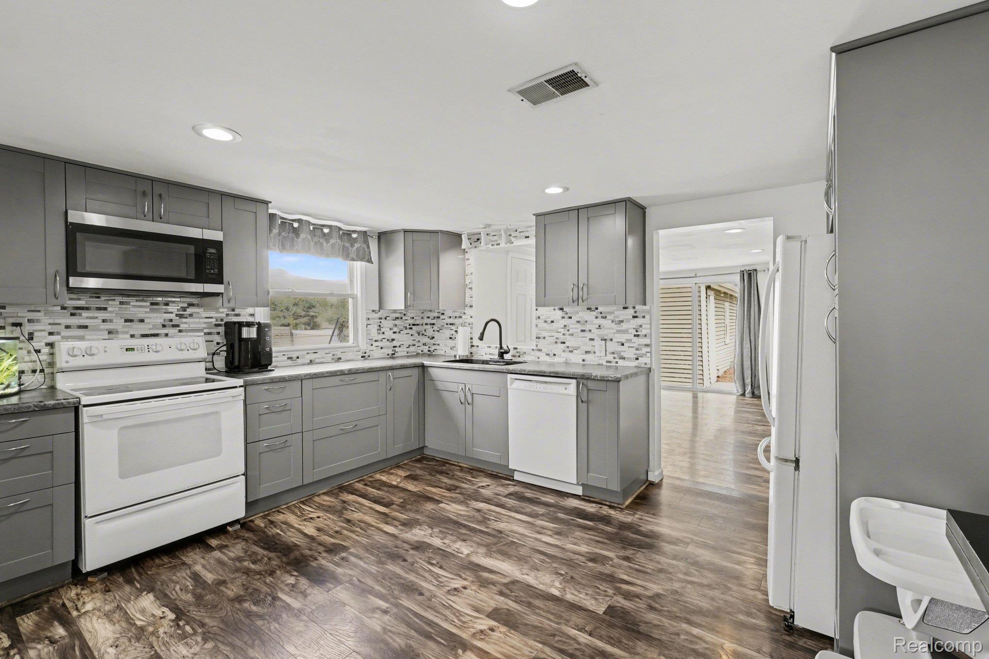 16485 Jennings Road Fenton, MI 48430 - Photo 14 of 27 Kitchen with gray cabinetry, white appliances, dark wood-style flooring, decorative backsplash, and recessed lighting
