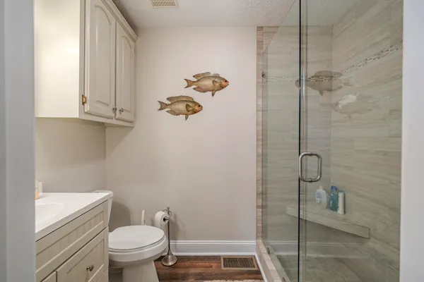 a bathroom with a granite countertop toilet a sink a mirror and a window