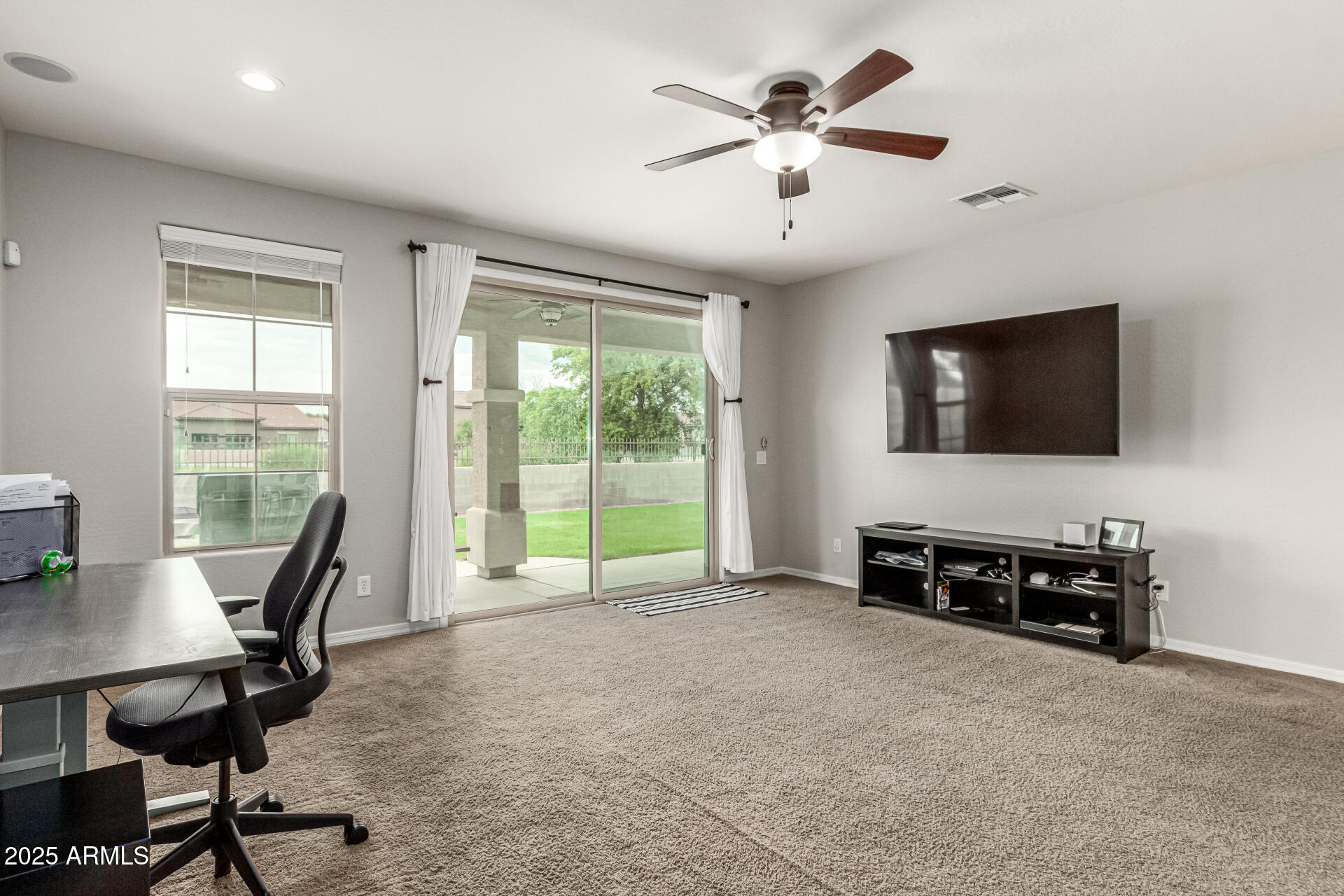 3135 East Ridgewood Lane Gilbert, AZ 85298 - Photo 11 of 39 a living room with furniture a flat screen tv and a floor to ceiling window