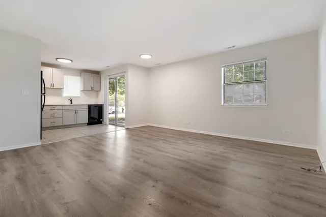 a view of empty room with kitchen and window