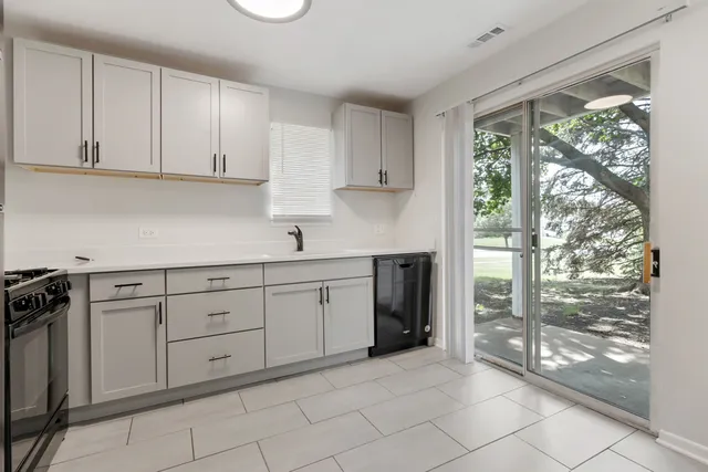 a kitchen with white cabinets and window