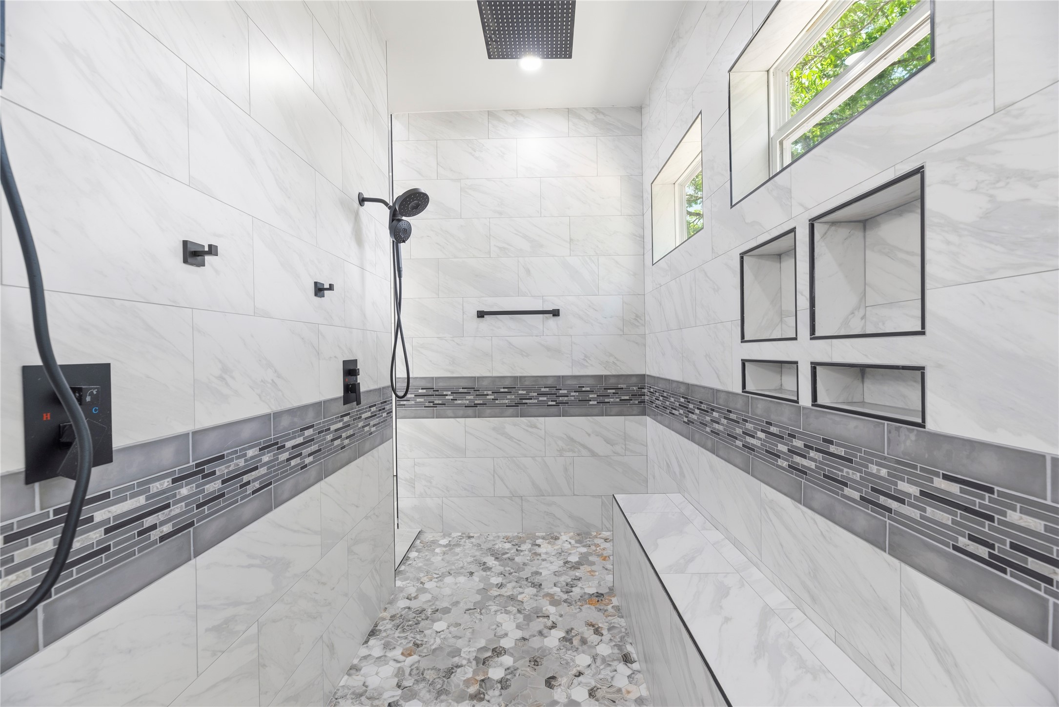 4607 Clayhead Road Richmond, TX 77406 - Photo 18 of 49 Showstopping oversized shower appointed with floor-to-ceiling tilework, rainfall fixtures, built-in seating, and custom niche detailing.