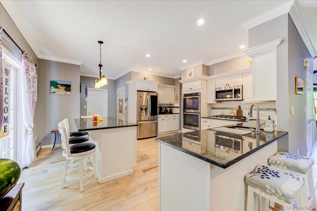 104 Wiccopee Road Putnam Valley, NY 10579 - Photo 11 of 50 Gourmet kitchen featuring white cabinetry, stainless steel appliances, dark stone countertops, wood-finish flooring, and a double island