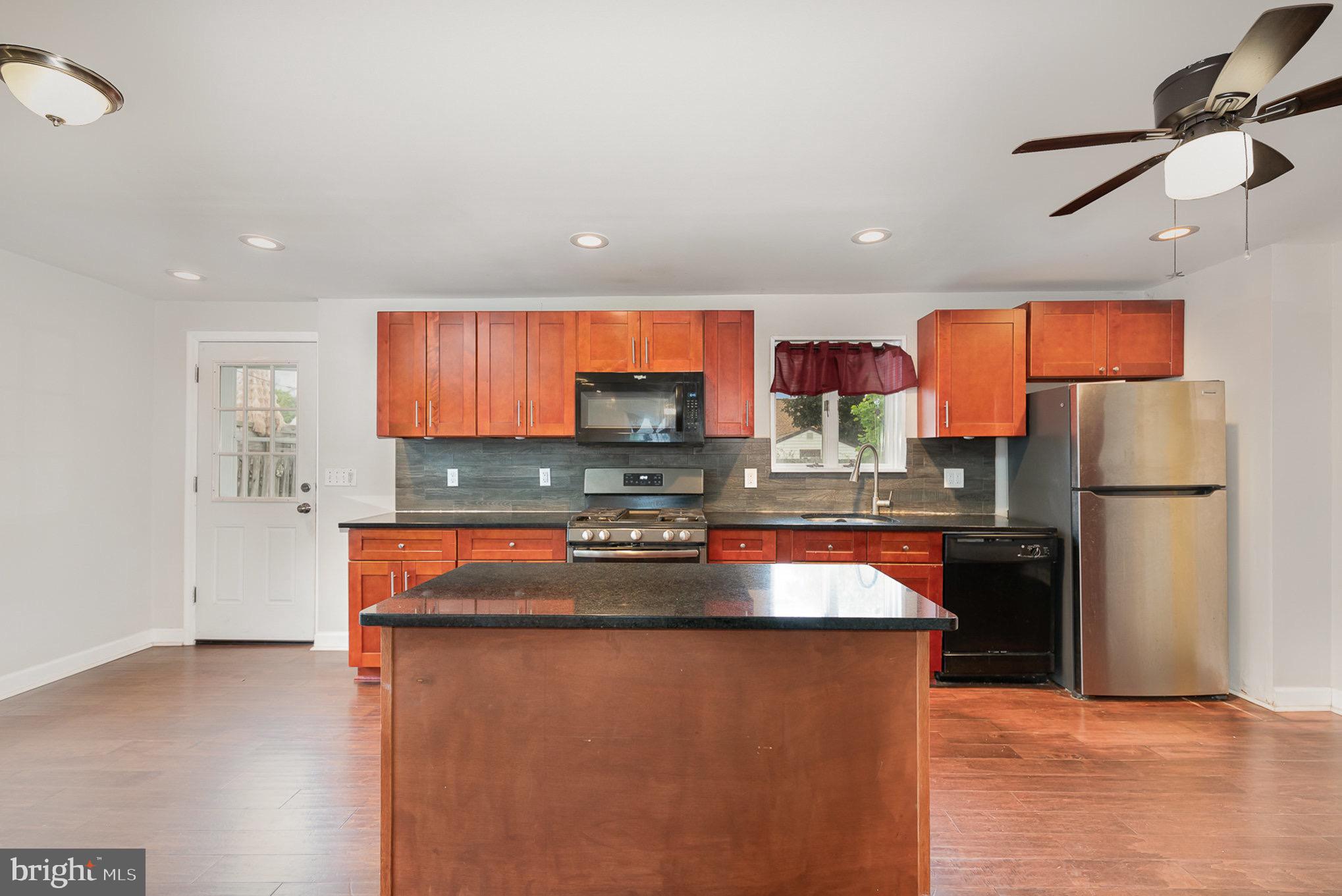 3402 Cornwall Road Dundalk, MD 21222 - Photo 8 of 25 a kitchen with stainless steel appliances granite countertop a refrigerator a stove and a sink with wooden floor